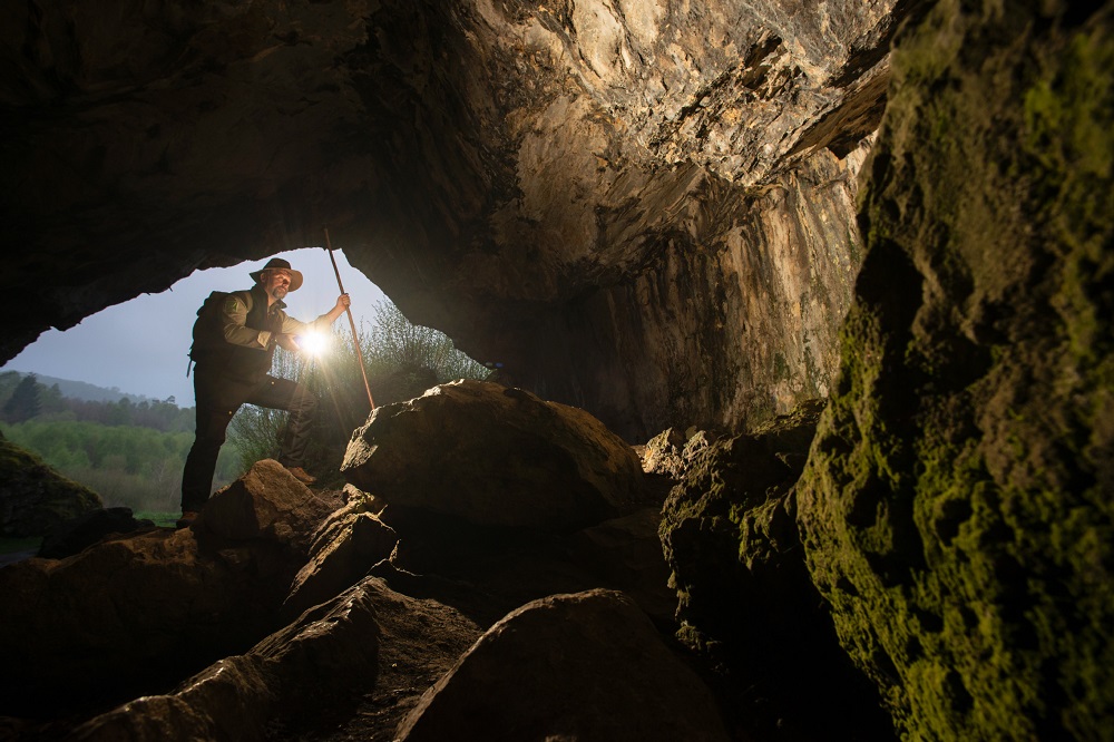 Ein Ranger leuchtet mit einer Taschenlampe in eine Höhle.